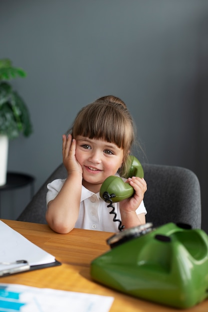 Porträt eines süßen Mädchens, das im Büro am Telefon mit Wählscheibe spricht
