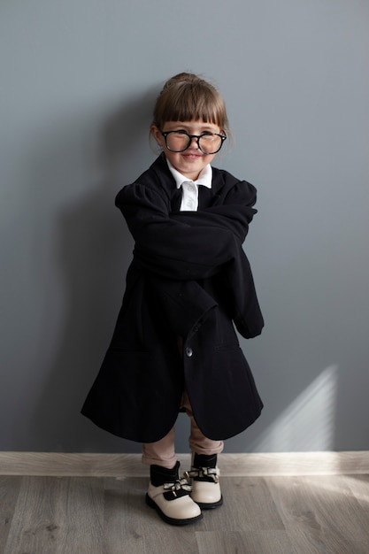 Porträt eines süßen Mädchens in übergroßem Mantel und Brille