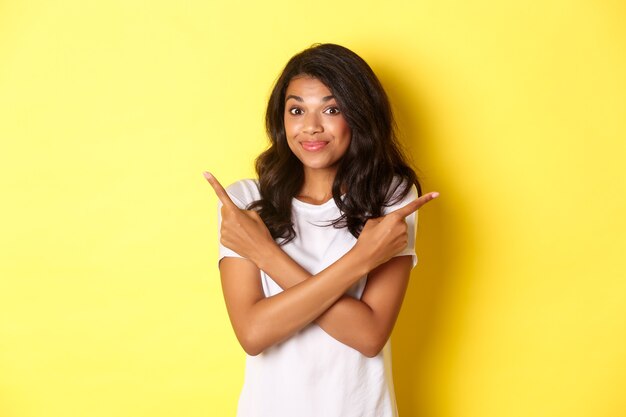 Porträt eines süßen, unentschlossenen afroamerikanischen Mädchens, das mit den Fingern seitwärts zeigt und mit den Schultern zuckt, um Adv zu fragen
