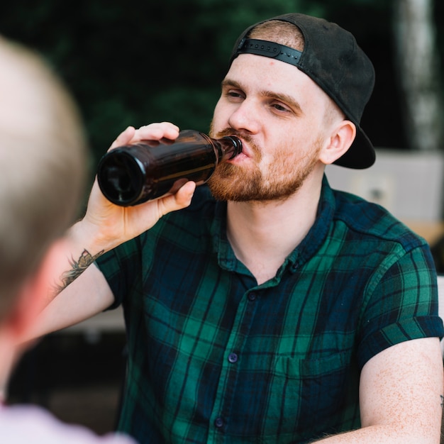 Porträt eines trinkenden Bieres des gutaussehenden Mannes in der Flasche