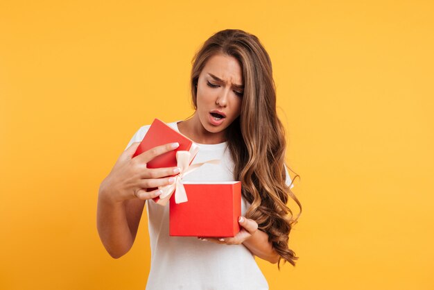 Porträt eines verärgerten enttäuschten Mädchens, das Geschenkbox öffnet