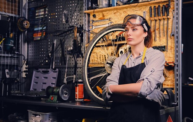 Porträt eines weiblichen Fahrradmechanikers über dem Hintergrund eines Werkzeugständers in einer Werkstatt.