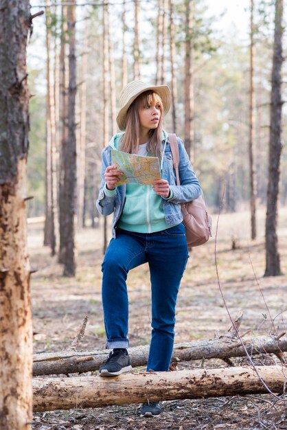 Porträt eines weiblichen Reisenden, der im Wald mit Karte steht