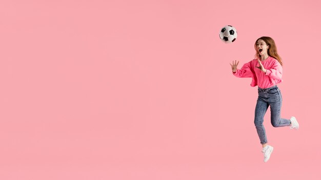 Kostenloses Foto porträt glückliche frau, die mit fußball springt