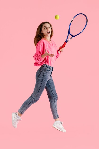 Porträt glückliche Frau, die mit Tennisschläger springt