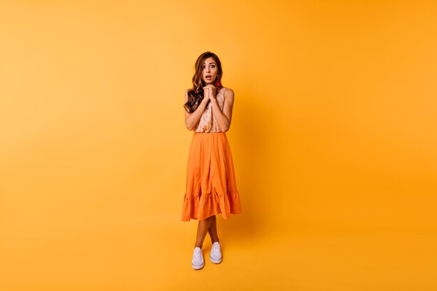 Porträt in voller Länge der Debonair-Ingwerfrau im langen Rock. Wunderschöne Dame trägt orange Kleidung, die im Studio aufwirft.