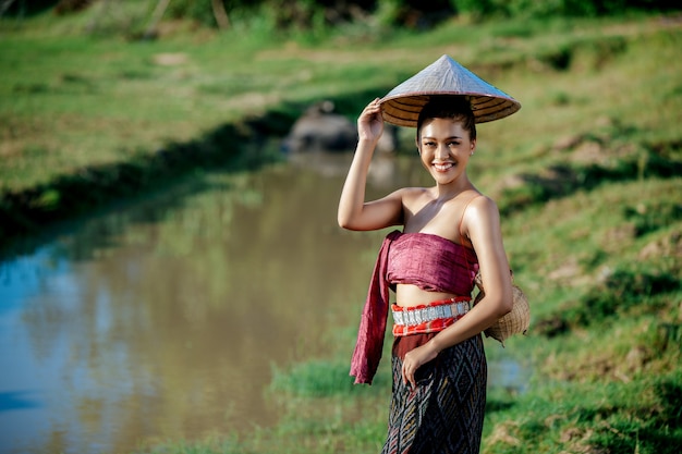 Porträt junge asiatische frau in schöner thailändischer traditioneller kleidung am reisfeld