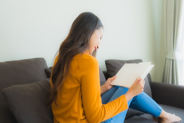 Porträt junge asiatische Frau las Buch auf Sofa Stuhl mit Kissen im Wohnzimmer