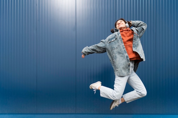 Kostenloses Foto porträt junge frau mit kopfhörern springen