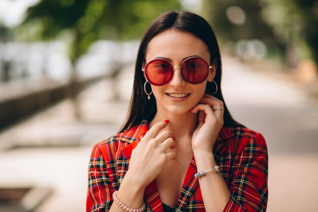 Porträt junger Dame in der roten Jacke und in der roten Sonnenbrille