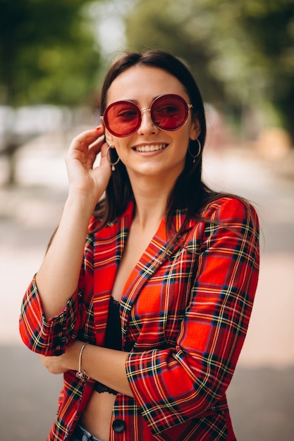 Porträt junger Dame in der roten Jacke und in der roten Sonnenbrille