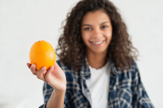 Kostenloses Foto porträt lächelnder dame eine orange anbietend