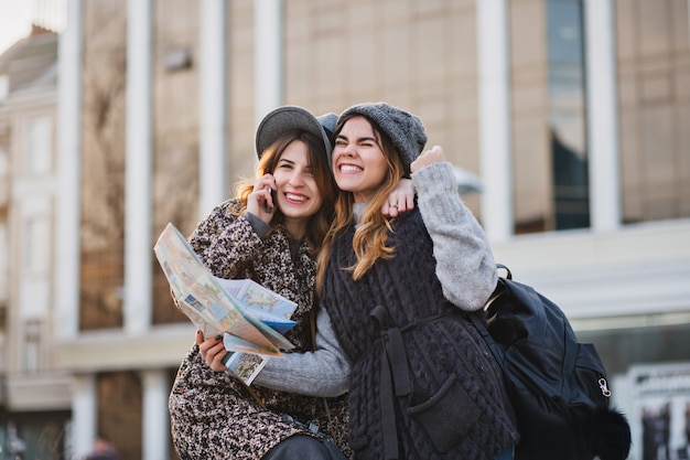 Porträt modische lächelnde Frauen, die helle Gefühle am sonnigen Tag in der Stadt ausdrücken. Viel Spaß beim gemeinsamen Reisen, schöne Momente freudiger Touristen, stilvoll, Urlaub genießen, telefonieren.