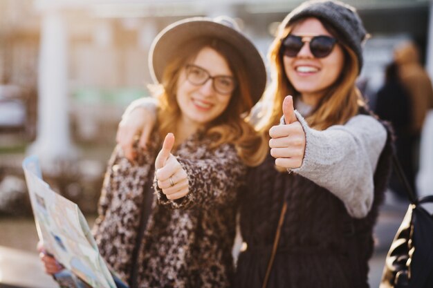 Porträt modische lächelnde Frauen, die helle Gefühle am sonnigen Tag in der Stadt ausdrücken. Viel Spaß beim gemeinsamen Reisen, schöne Momente mit fröhlichen Touristen, stilvollem Aussehen, Urlaub genießen, Glück.