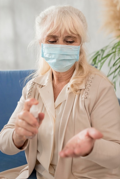 Kostenloses Foto porträt oma mit maske mit händedesinfektionsmittel