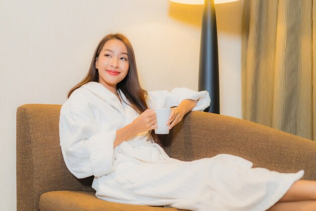 Porträt schöne junge asiatische Frau, die auf Sofa im Wohnzimmerinnenraum entspannt