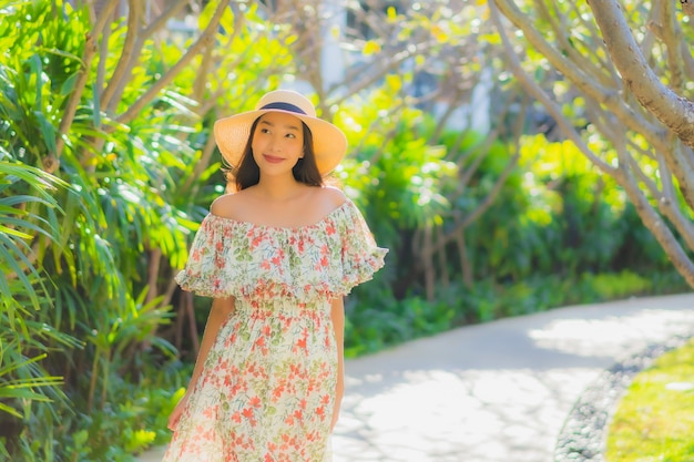 Porträt schöne junge asiatische Frau, die mit glücklich um Gartenblick im Freien geht