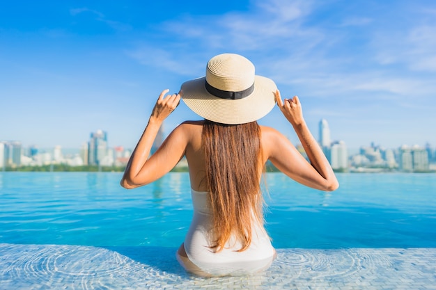 Porträt schöne junge asiatische Frau, die sich um Freibad mit Blick auf die Stadt entspannt