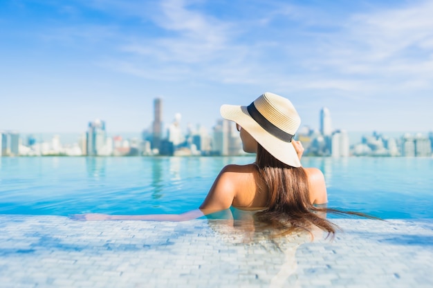 Porträt schöne junge asiatische Frau, die sich um Freibad mit Blick auf die Stadt entspannt