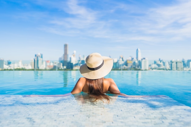 Porträt schöne junge asiatische Frau, die sich um Freibad mit Blick auf die Stadt entspannt