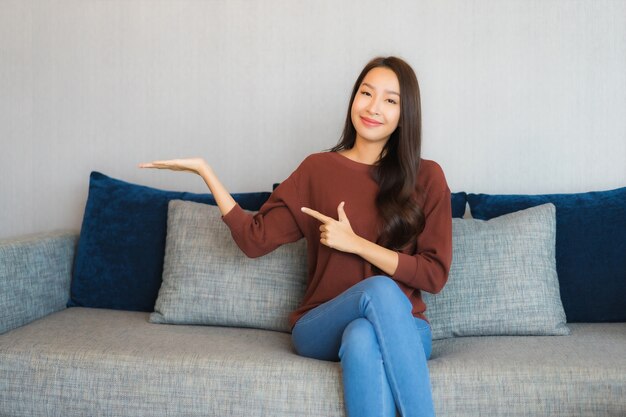 Porträt schöne junge asiatische Frau entspannen Lächeln auf dem Sofa im Wohnzimmer Interieur