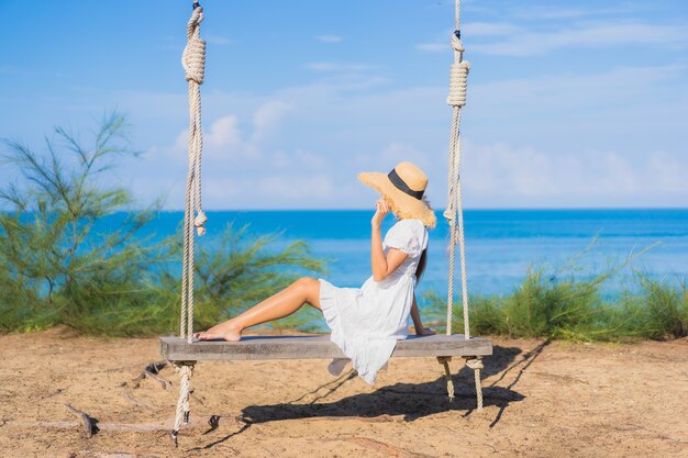 Porträt schöne junge asiatische Frau entspannen Lächeln auf Schaukel um Strand Meer Ozean für Naturreisen im Urlaub