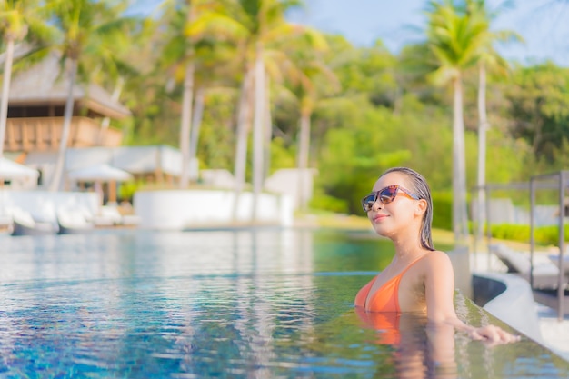 Porträt schöne junge asiatische Frau entspannen Lächeln Freizeit um Freibad im Resort Hotel mit Meerblick