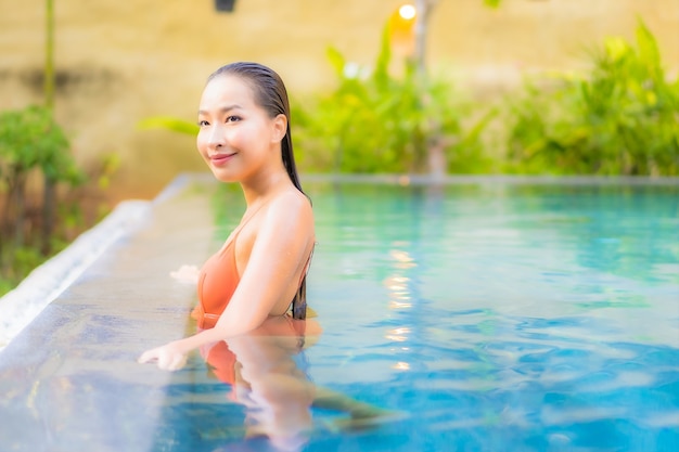 Porträt schöne junge asiatische Frau genießen entspannen um Schwimmbad für Freizeiturlaub