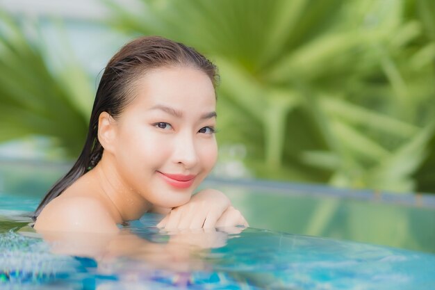 Porträt schöne junge asiatische Frau im Freien im Schwimmbad in Urlaubsreise entspannen