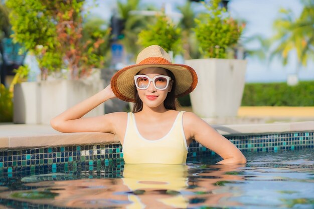 Porträt schöne junge asiatische Frau im Freien im Schwimmbad in Urlaubsreise entspannen