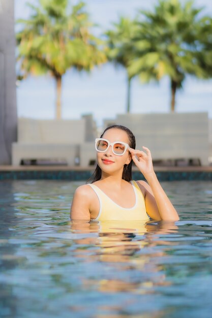 Porträt schöne junge asiatische Frau im Freien im Schwimmbad in Urlaubsreise entspannen