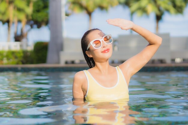 Porträt schöne junge asiatische Frau im Freien im Schwimmbad in Urlaubsreise entspannen