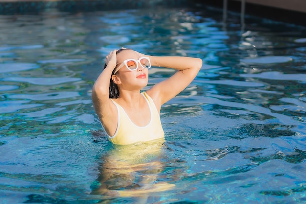 Porträt schöne junge asiatische Frau im Freien im Schwimmbad in Urlaubsreise entspannen