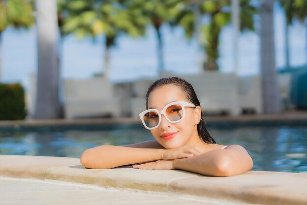 Porträt schöne junge asiatische Frau im Freien im Schwimmbad in Urlaubsreise entspannen