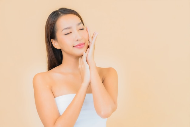 Porträt schöne junge asiatische Frau im Spa mit natürlichem Make-up auf Beige