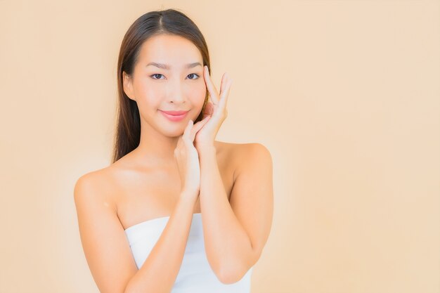 Porträt schöne junge asiatische Frau im Spa mit natürlichem Make-up auf Beige