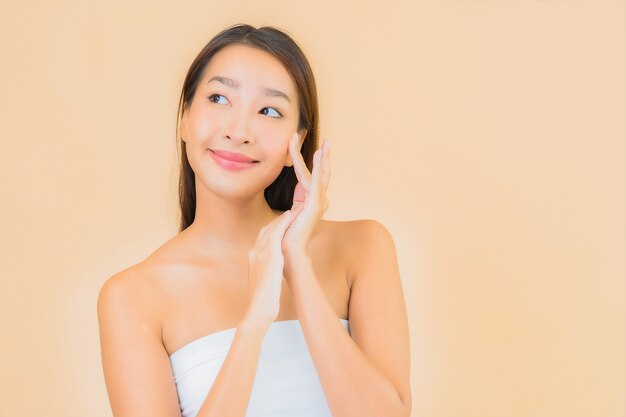 Porträt schöne junge asiatische Frau im Spa mit natürlichem Make-up auf Beige