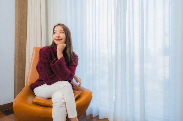 Porträt schöne junge asiatische Frau Lächeln entspannen auf Sofa im Wohnzimmer Interieur