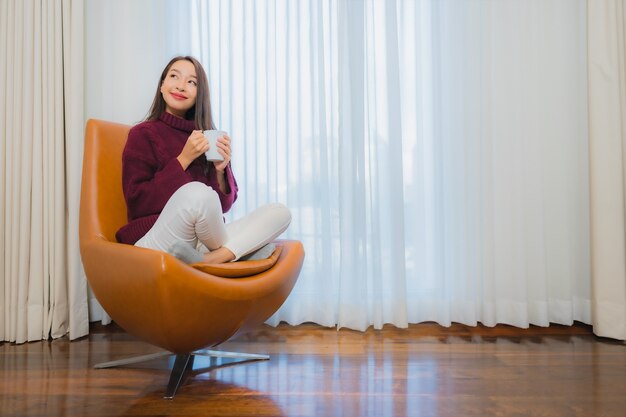 Porträt schöne junge asiatische Frau Lächeln entspannen auf Sofa im Wohnzimmer Interieur