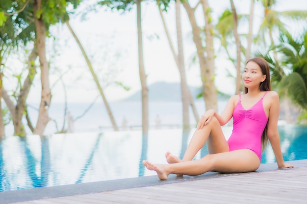 Porträt schöne junge asiatische Frau Lächeln entspannen um Außenpool im Resort Hotel auf Urlaub Urlaub Reise Reise