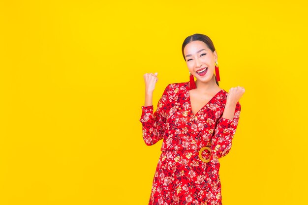 Porträt schöne junge asiatische Frau lächeln in Aktion im chinesischen Neujahrskonzept auf Farbwand