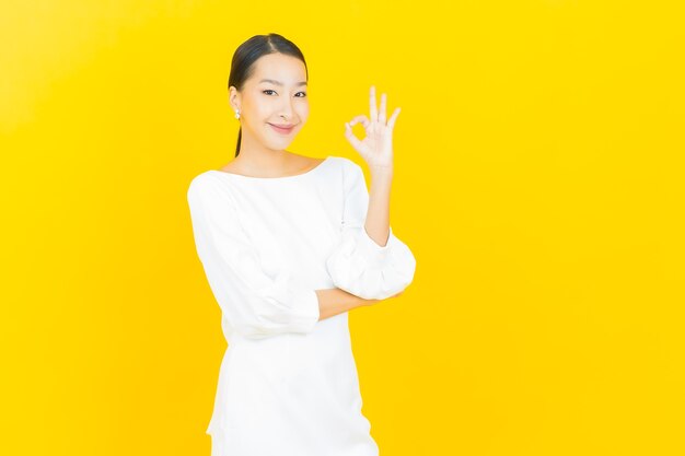 Porträt schöne junge asiatische Frau Lächeln mit Aktion auf Gelb with