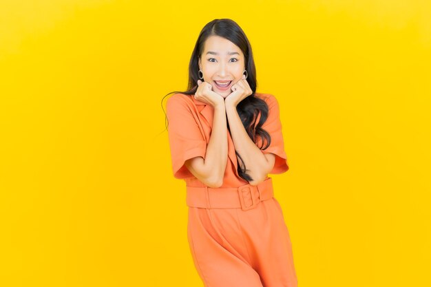 Porträt schöne junge asiatische Frau lächeln mit Aktion auf gelb