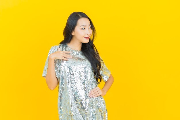 Porträt schöne junge asiatische Frau lächeln mit Aktion auf gelb