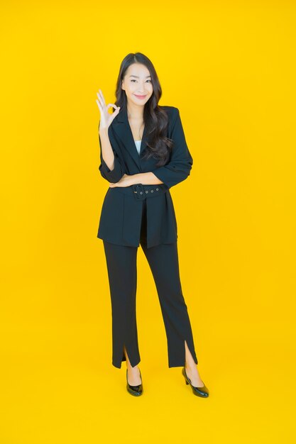 Porträt schöne junge asiatische Frau Lächeln mit Aktion auf Gelb