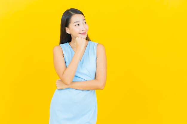Porträt schöne junge asiatische Frau lächeln mit Aktion auf gelber Farbe Wand