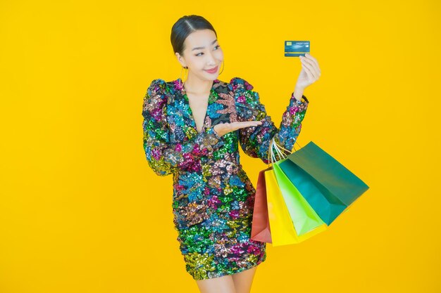 Porträt schöne junge asiatische Frau Lächeln mit Einkaufstasche auf Gelb