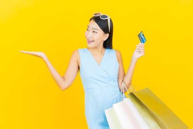Porträt schöne junge asiatische Frau lächeln mit Einkaufstasche auf gelber Farbe Wand