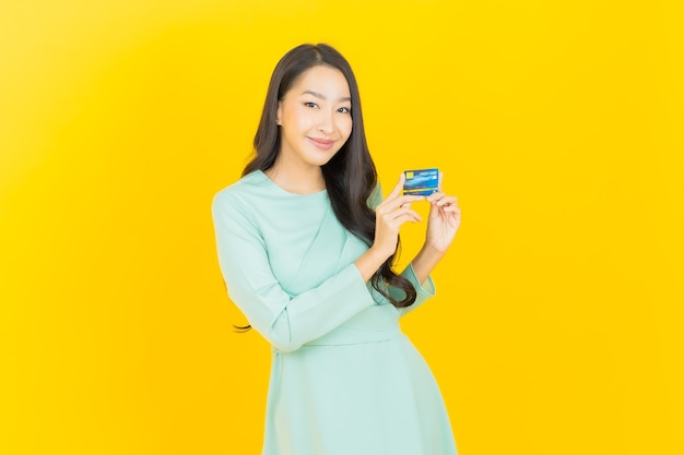 Porträt schöne junge asiatische Frau Lächeln mit Kreditkarte auf Gelb credit