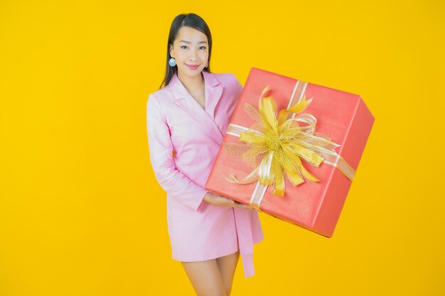 Porträt schöne junge asiatische Frau Lächeln mit roter Geschenkbox auf Farbhintergrund